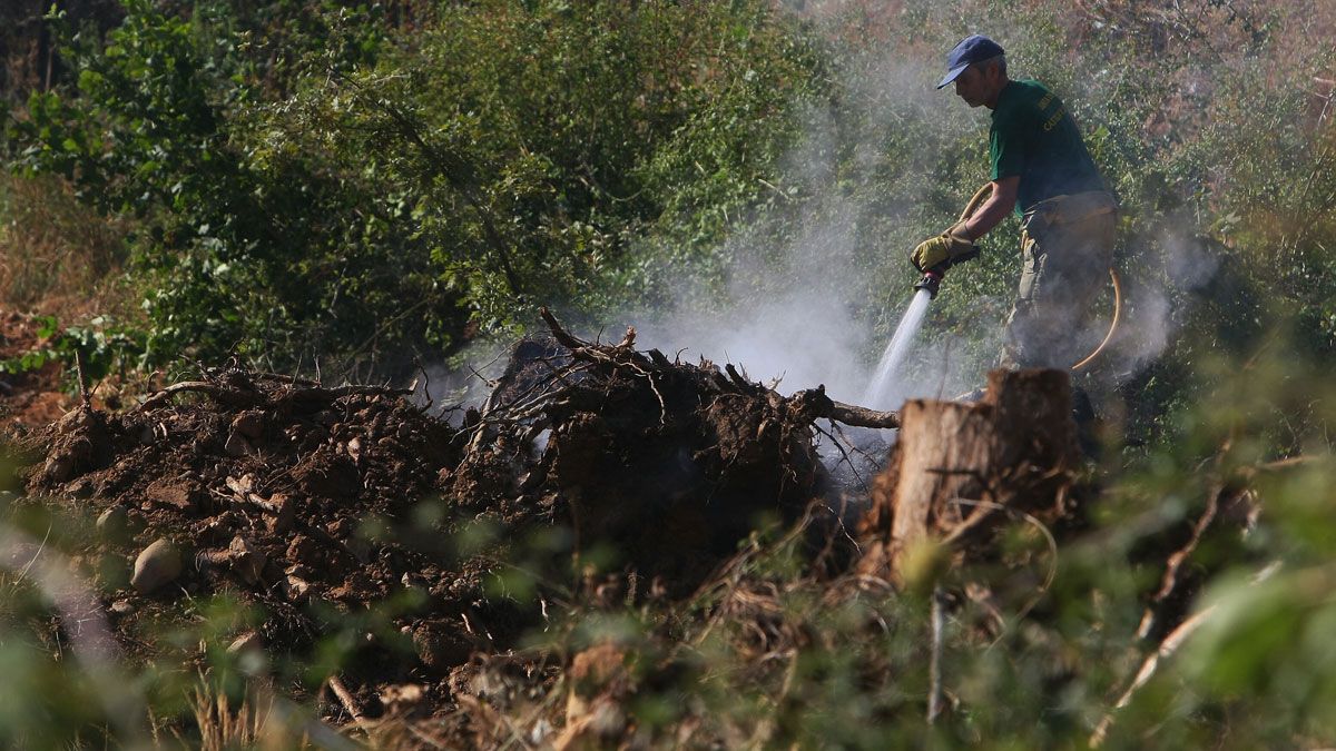 Un operario, enfriando la zona quemada tras el incendio. | César Sánchez