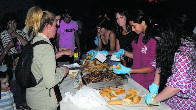 La cadena funciona a la perfección;los mozos preparan la panceta de los bocadillos y las mozas finalizan el proceso colocándola en el pan. | F. FERNÁNDEZ