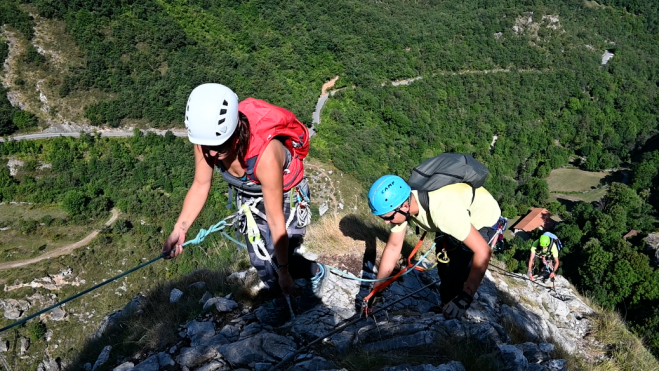 Deportista ciego, casco azul, acompañado de sus guías.