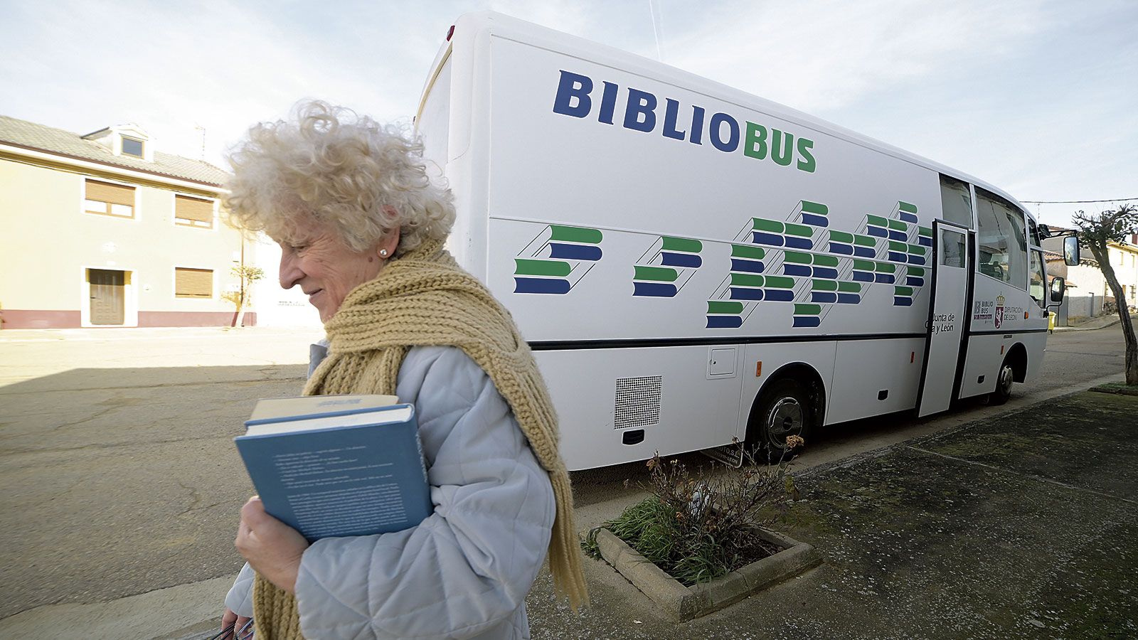 Una de las usuarias del servicio de bibliobuses de León. Vecina de Valdavida, sale contenta del vehículo sujeta a ‘El problema final’ de Pérez Reverte. | MAURICIO PEÑA