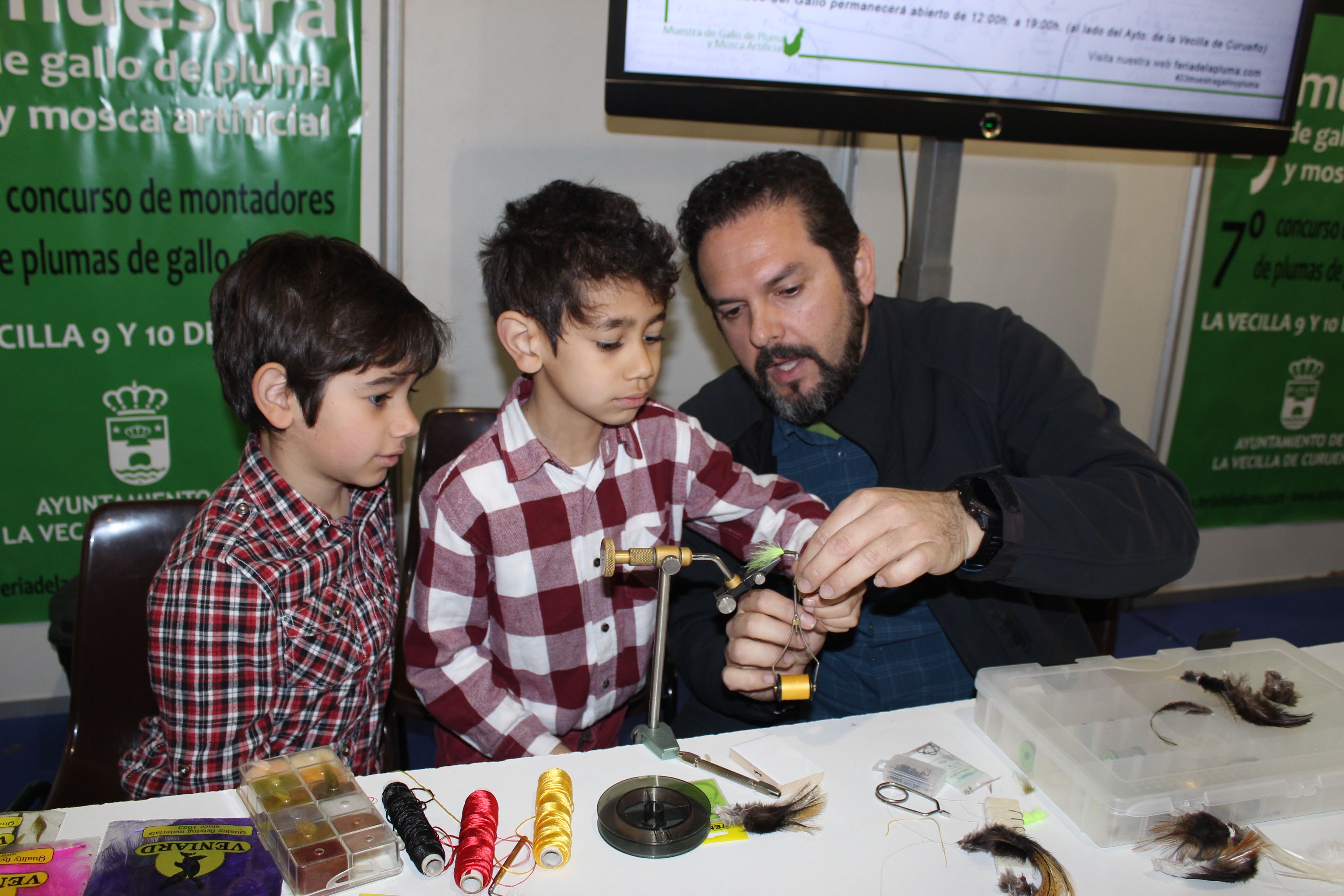 Dos niños aprendiendo el arte del montaje de la mosca en una de las ediciones anteriores de la feria. ALFREDO HURTADO